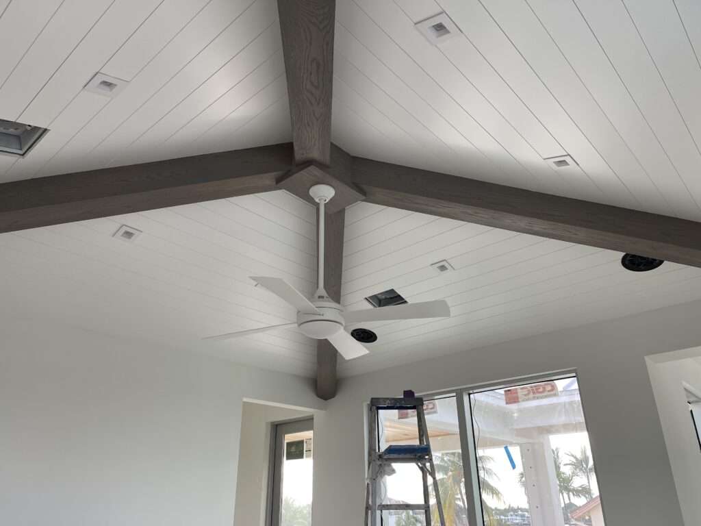 Vaulted ceiling with wooden beams and ceiling fan.