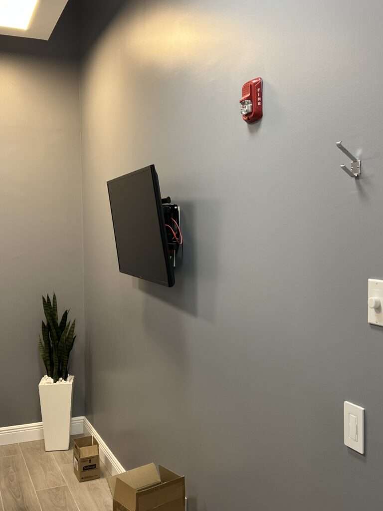 Modern room with wall-mounted TV and fire alarm.