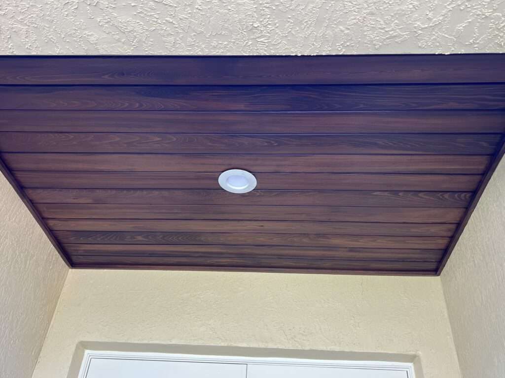 Wooden ceiling with recessed light fixture in entryway.