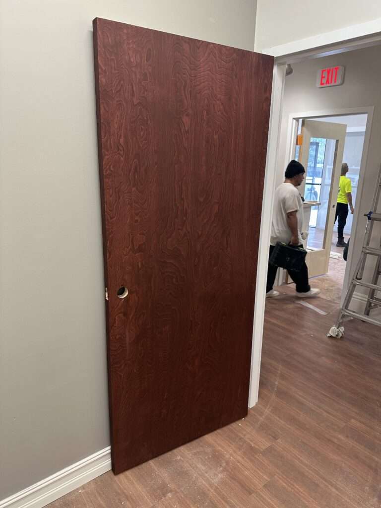 Unattached wooden door leaning against a wall indoors.