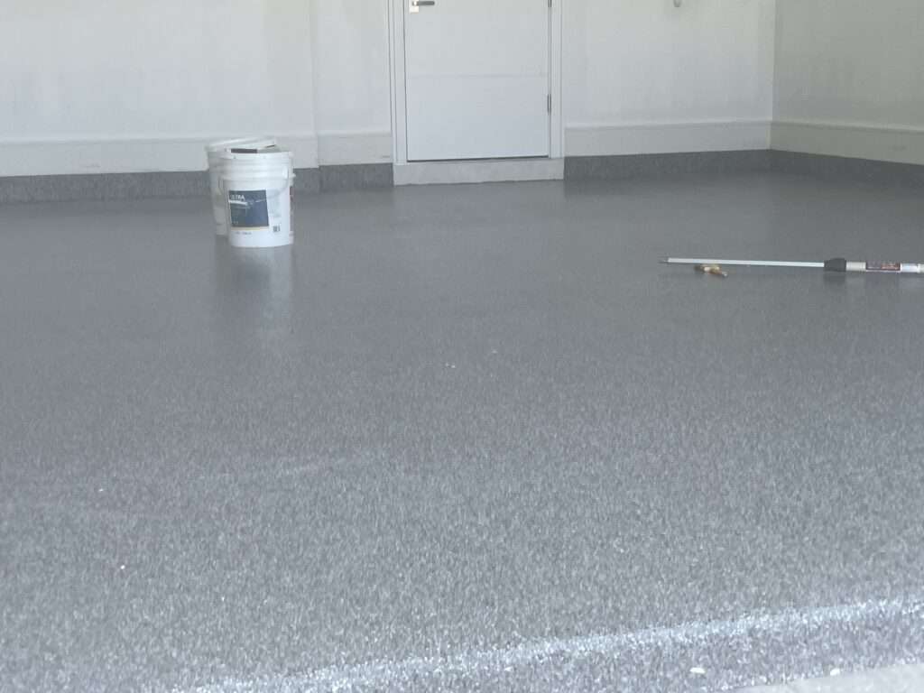 Freshly painted garage floor with paint supplies nearby.