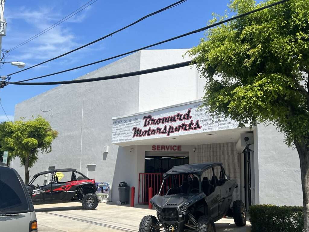 Motorsports dealership building with ATVs outside under clear sky.