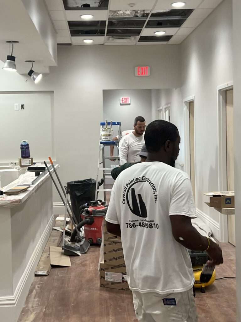 Workers renovating office interior with equipment and materials.