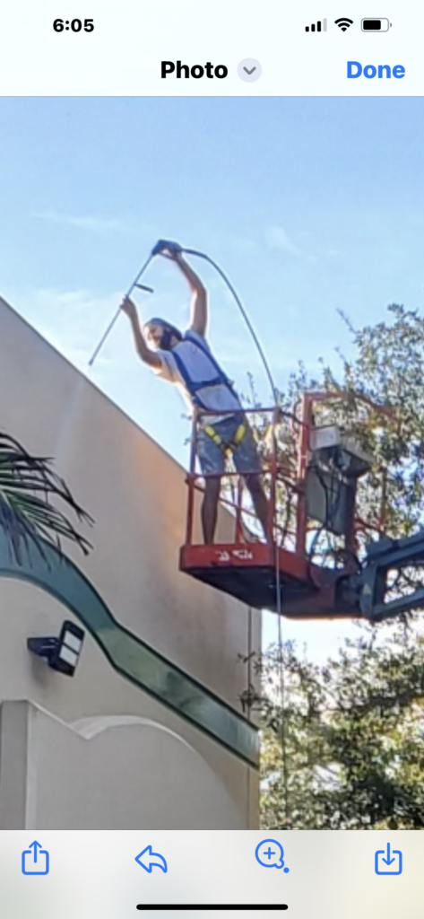 Man on lift performing outdoor maintenance.