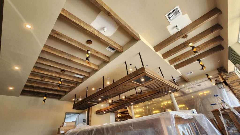Modern restaurant interior with wooden beams and unique lighting.