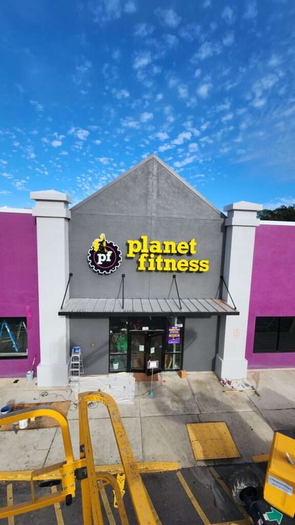 Exterior of Planet Fitness gym with clear blue sky.